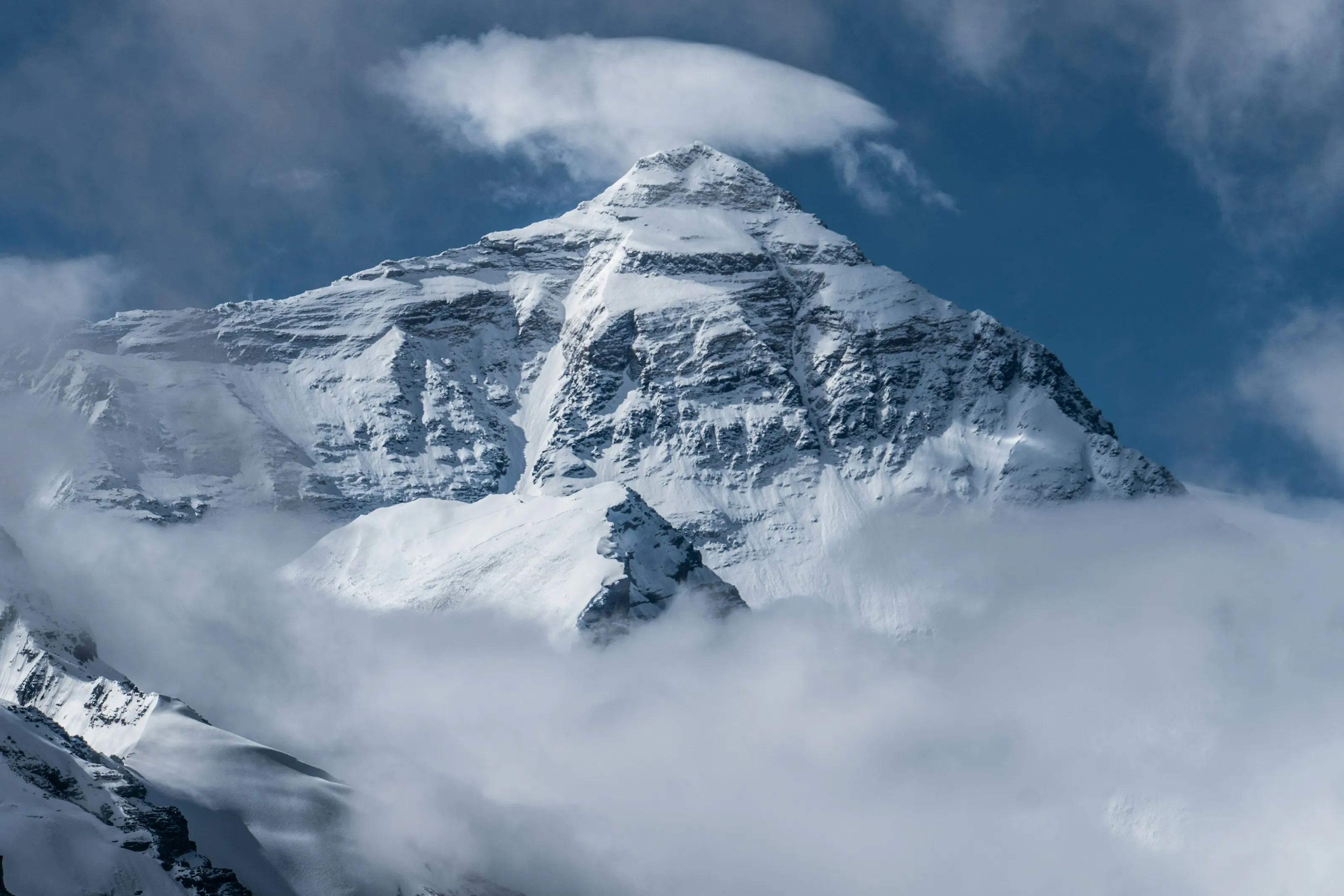The north face of Mount Everest rising above the clouds